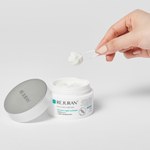 Person applying Rejuran cream with a applicator on a light gray background