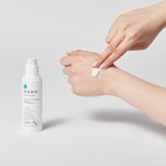 Person applying cream to hand with Belijur bottle on light gray background
